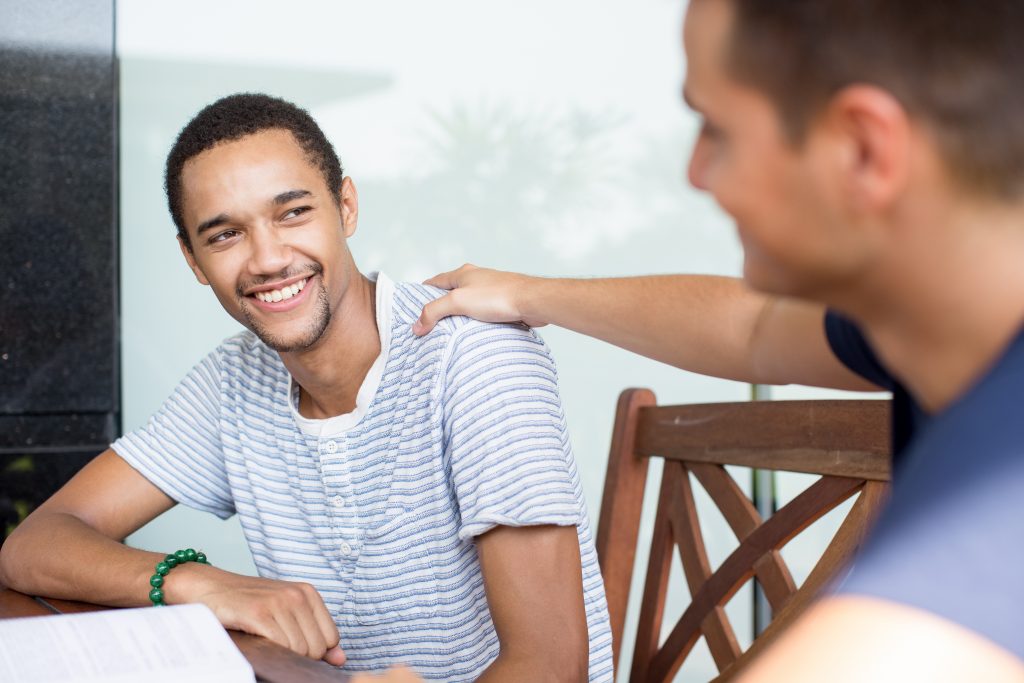 Smiling guy receiving support from friend